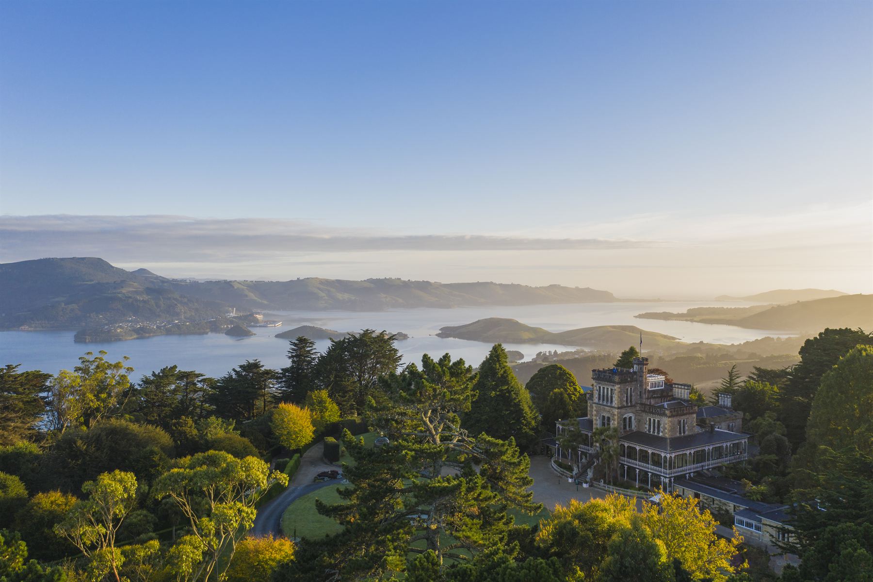 Sunrise over the Otago Harbour, with the castle among the trees on the right