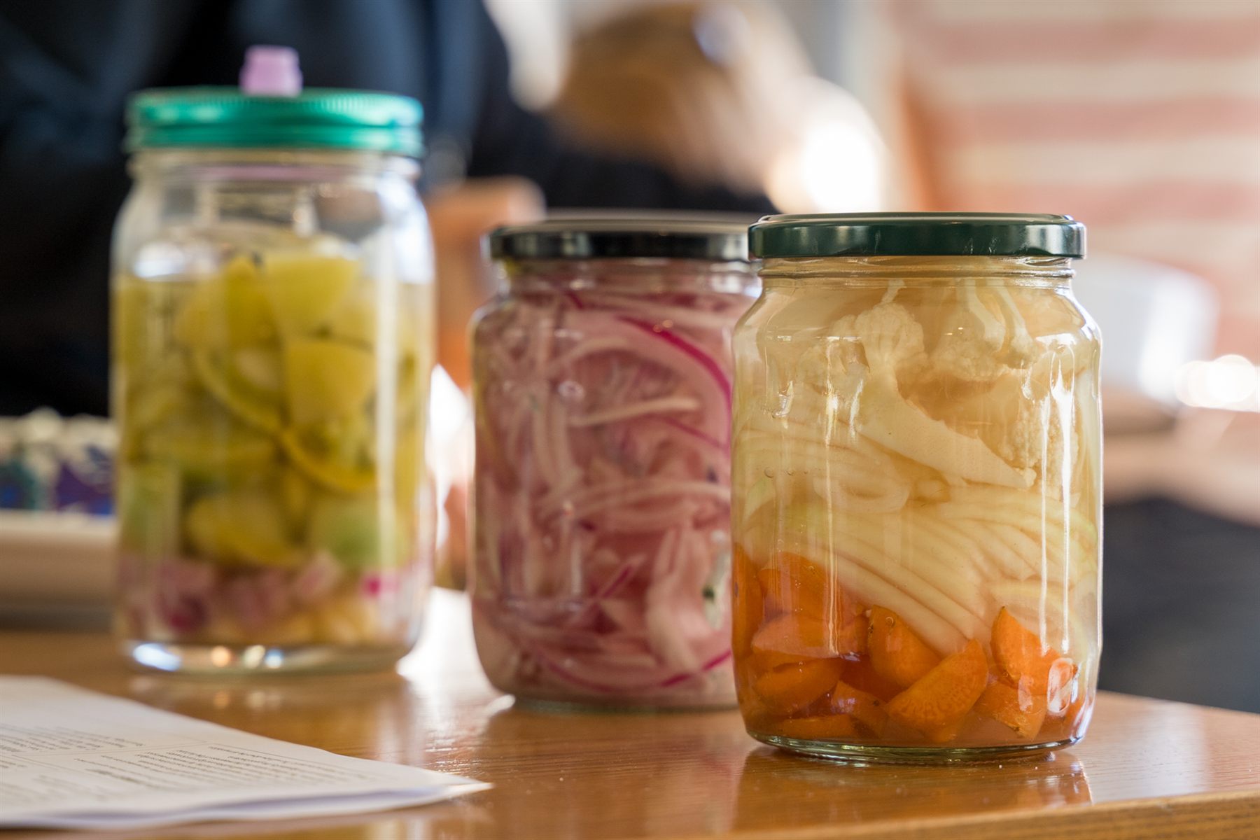Jars of fermented lemons, pickled red onion and cauliflower with carrot on a kitchen table